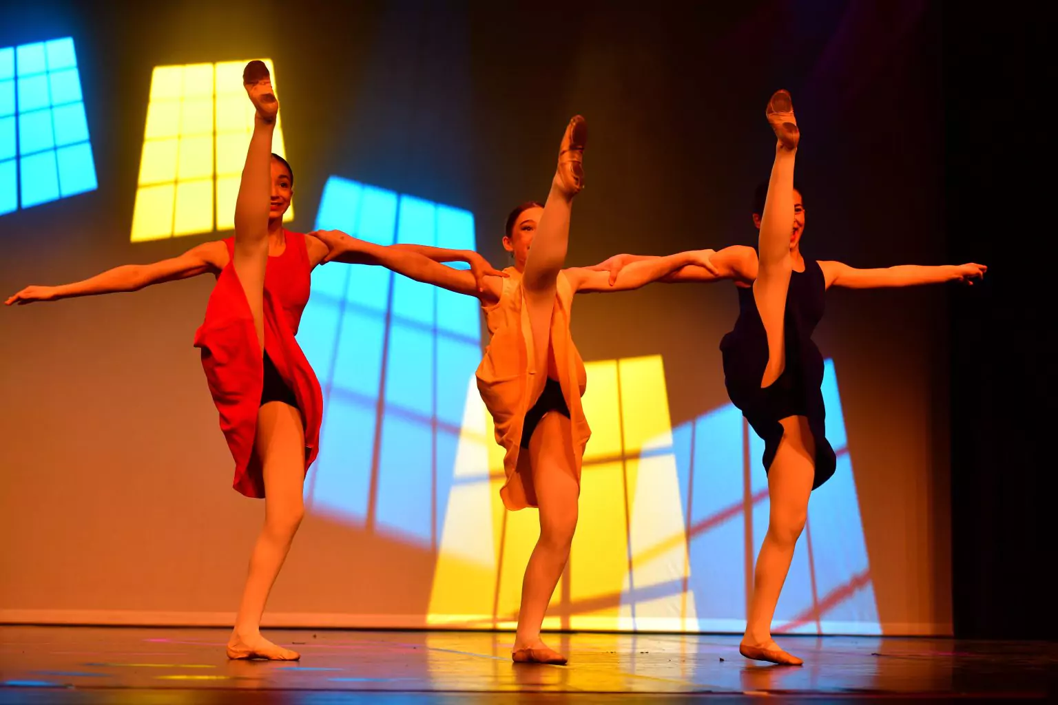 Drei Tänzerinnen in einer akrobatischen Pose mit hoch ausgestrecktem Bein